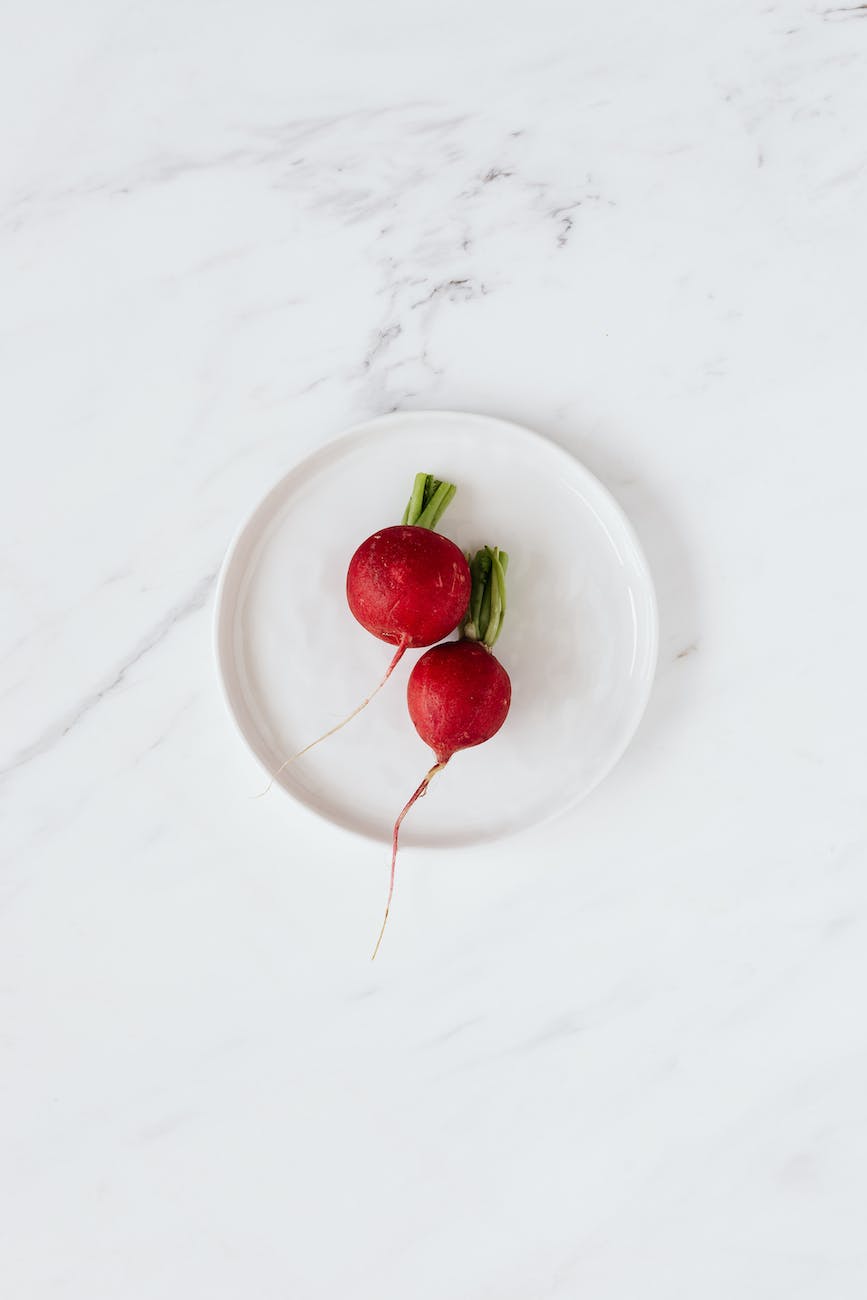 fresh radishes in ceramic bowl placed on marble table